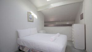 Une chambre à coucher avec un lit, une table de chevet, une commode et une fenêtre.