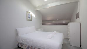 Quarto com cama, mesa de cabeceira, penteadeira e janela.