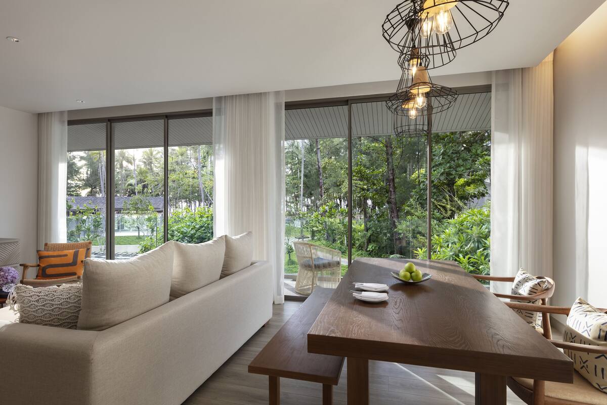 Una sala moderna con una mesa de comedor de madera, un sofá y una silla de mimbre.