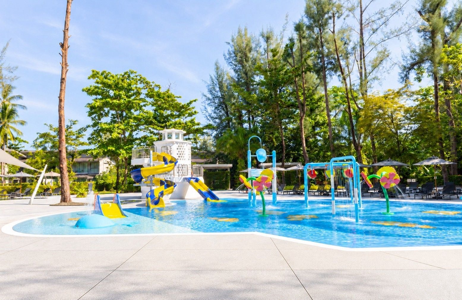 A swimming pool with slides and water features, surrounded by palm trees and lounge chairs.