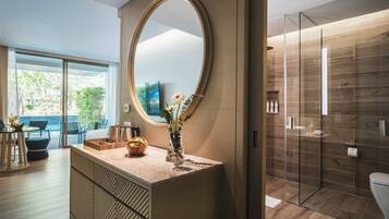 A modern bathroom with a large mirror, wooden flooring, and a glass shower enclosure.