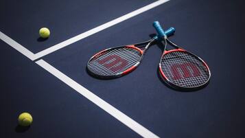 A tennis court with two tennis rackets and two tennis balls.