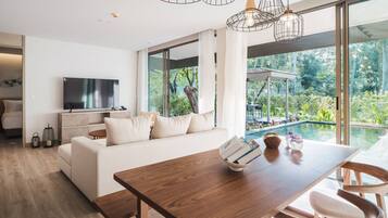 A modern living room with a wooden dining table, a sofa, and a TV.