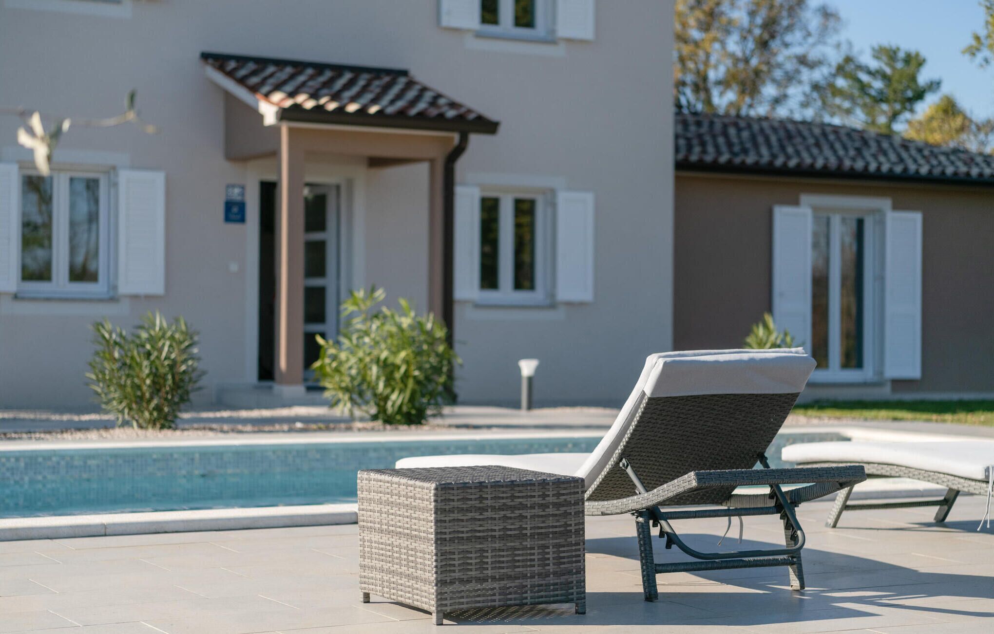 A poolside area with a lounge chair and a small wicker table.