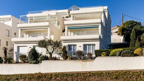 A modern multi-story building with balconies, a flat roof, and a concrete retaining wall. - Cap Ras 04 Comfortable apartment close to the sea (Llança)