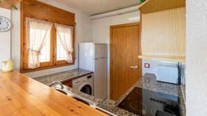 A compact kitchen with a washing machine, a refrigerator, and a sink. - Cap Ras 04 Comfortable apartment close to the sea (Llança)