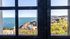 A view through a window with a coastal landscape, including buildings and the sea.