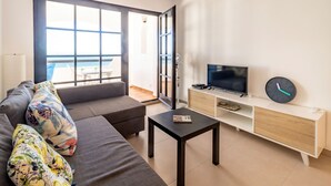A modern living room with a sofa, a coffee table, a TV, and a clock on the wall.