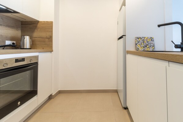 A compact kitchen with a built-in oven, a coffee maker, and a refrigerator.