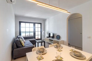 Una sala moderna con sofá, mesa de comedor para dos personas y televisor.