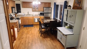 Kitchen area with a central island, stainless steel appliances, and a dining table.
