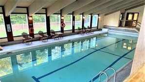Una piscina con acqua cristallina, circondata da lettini e una zona coperta con finestre.