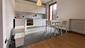 Una cucina moderna con mobili bianchi, forno integrato e zona pranzo con tavolo e sedie.