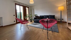 Un soggiorno moderno con un divano, due poltrone rosse, una lampada da terra e una pianta in vaso.