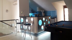 Une cuisine moderne dotée d’un îlot central, de tabourets de bar et d’une table de billard.