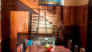 A wooden dining table with chairs, a chandelier, and a staircase in the background. - Casa Rogelio Inchauspi Bastida TRINIDAD (Trinidad)