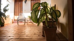 A wooden-floored patio with a potted plant, a chair, and a table. - Casa Rogelio Inchauspi Bastida TRINIDAD (Trinidad)
