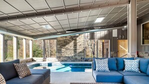 A modern outdoor living area with a pool, stone wall, and comfortable seating. - Heated Large Indoor POOL, VIEWS, Firepit, Location! 6BRCabin-sleeps 20 Game Room (Sevierville)