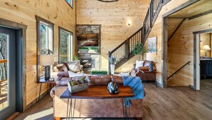 A spacious living area with a wooden interior, a fireplace, a staircase, and a dining table. - Heated Large Indoor POOL, VIEWS, Firepit, Location! 6BRCabin-sleeps 20 Game Room (Sevierville)
