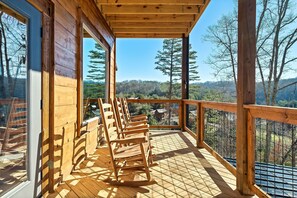 Relax on the deck with a clear view of the surrounding landscape, featuring a seating area with comfortable rocking chairs and a wooden railing for safety and privacy.