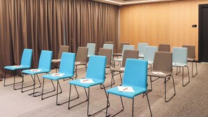 A conference room with rows of chairs, a curtain, and a wooden wall. - Novotel Living Almaty Jetisu (Almaty)