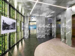 A modern interior with a curved pathway, a glass elevator, and a wall with a perforated metal pattern. - Novotel Living Almaty Jetisu (Almaty)