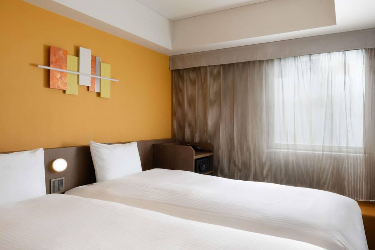 Een hotelkamer met een groot bed, een bureau en een raam met gordijnen.