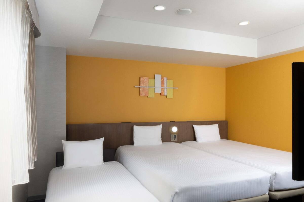 Een hotelkamer met twee bedden, een moderne lamp en een kunstwerk aan de muur.