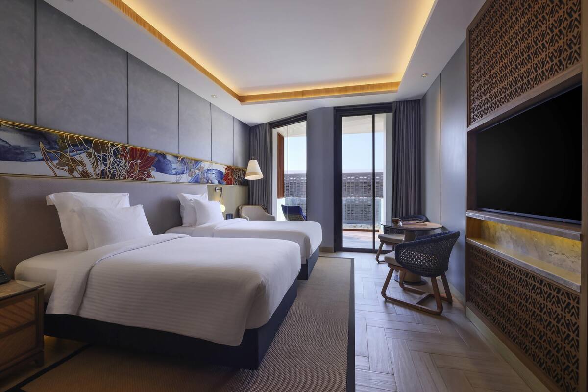 Une chambre d’hôtel avec un grand lit, un bureau, une chaise, une télévision et une vue sur la ville.