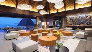 Ein geräumiger Lounge-Bereich mit runden Holztischen, Sofas und Meerblick.