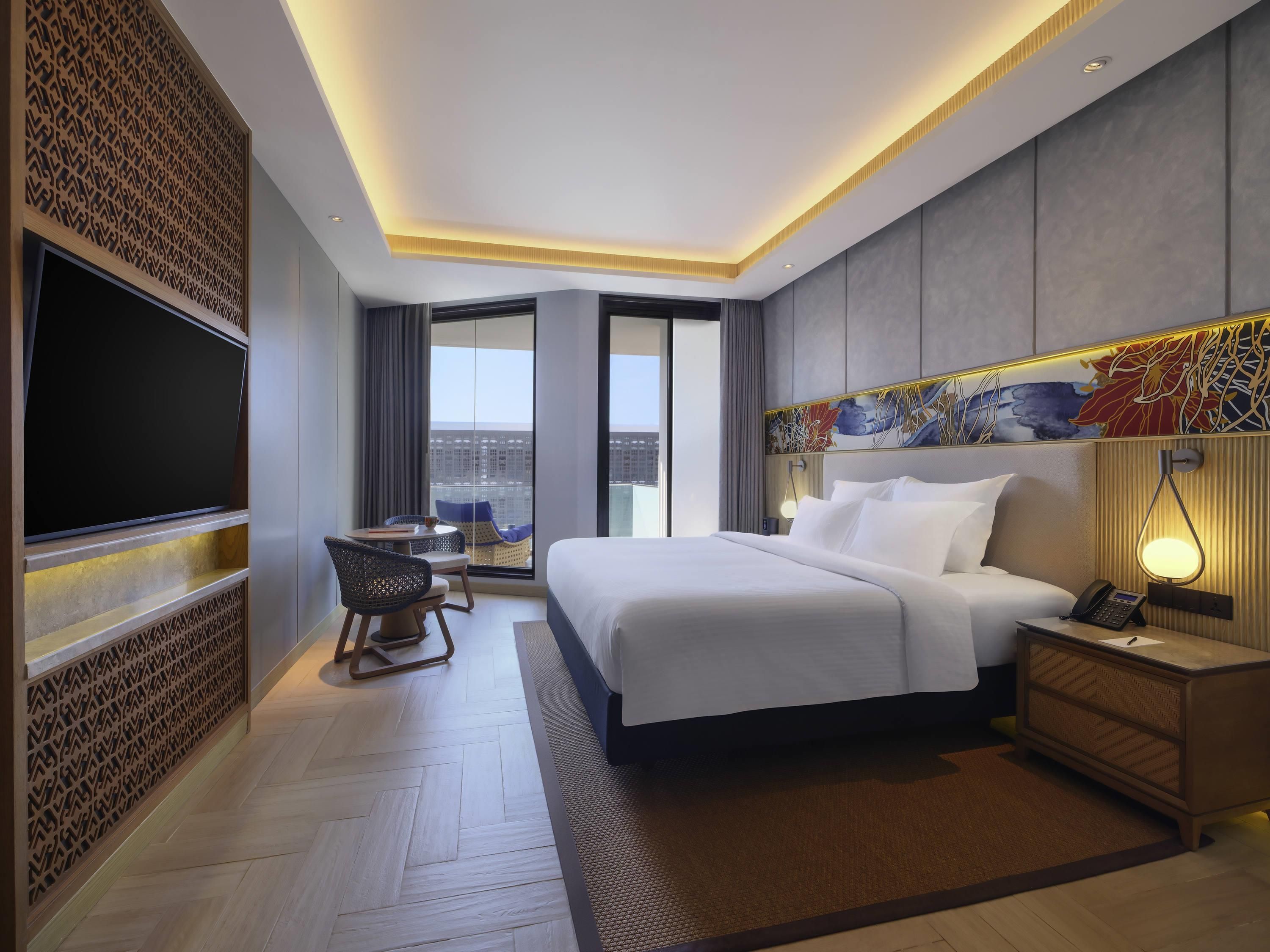 Une chambre d’hôtel avec un grand lit, une table de chevet et un téléviseur à écran plat fixé au mur.