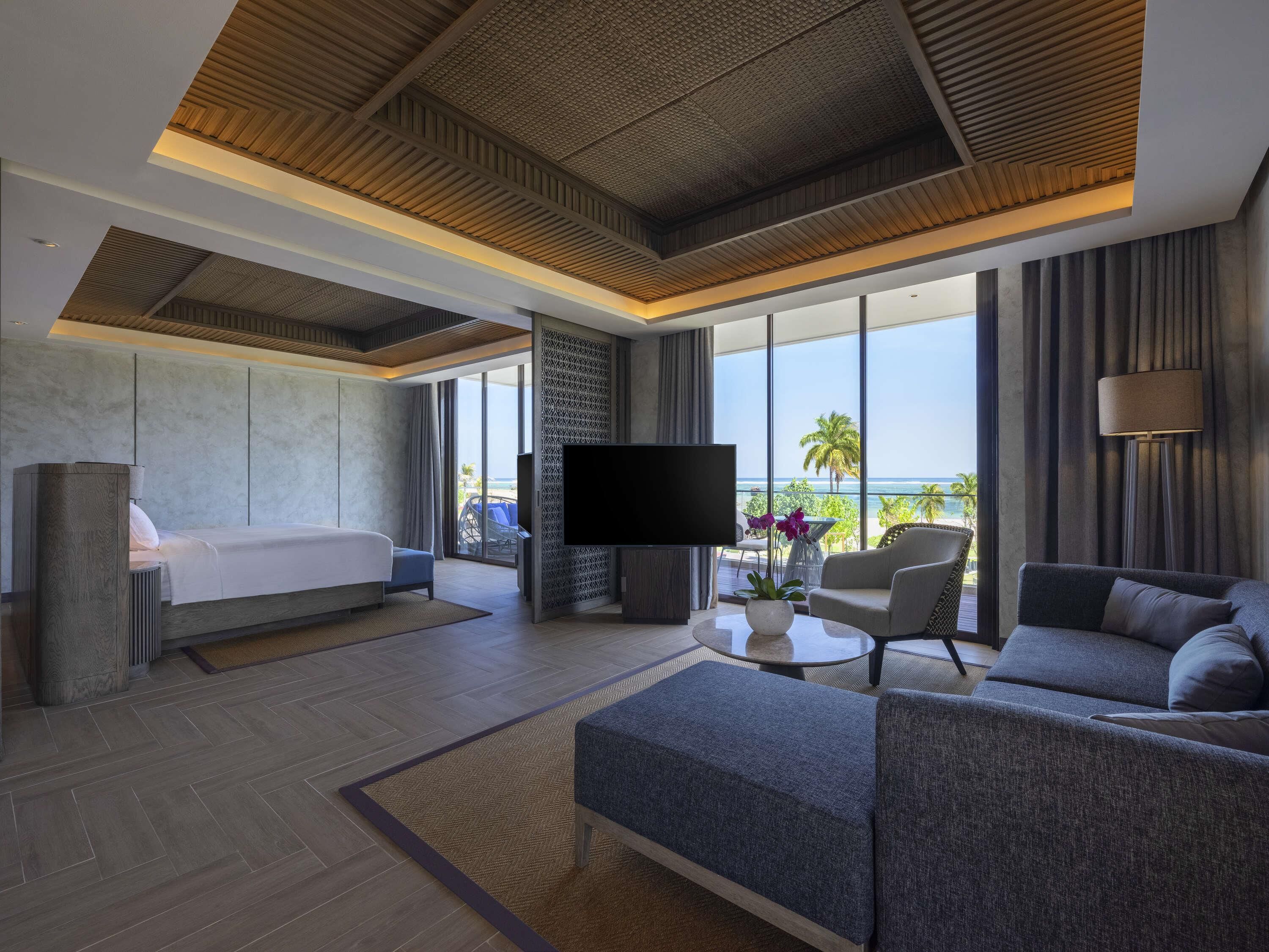 Een moderne hotelkamer met een bed, bank, televisie en uitzicht op de oceaan.