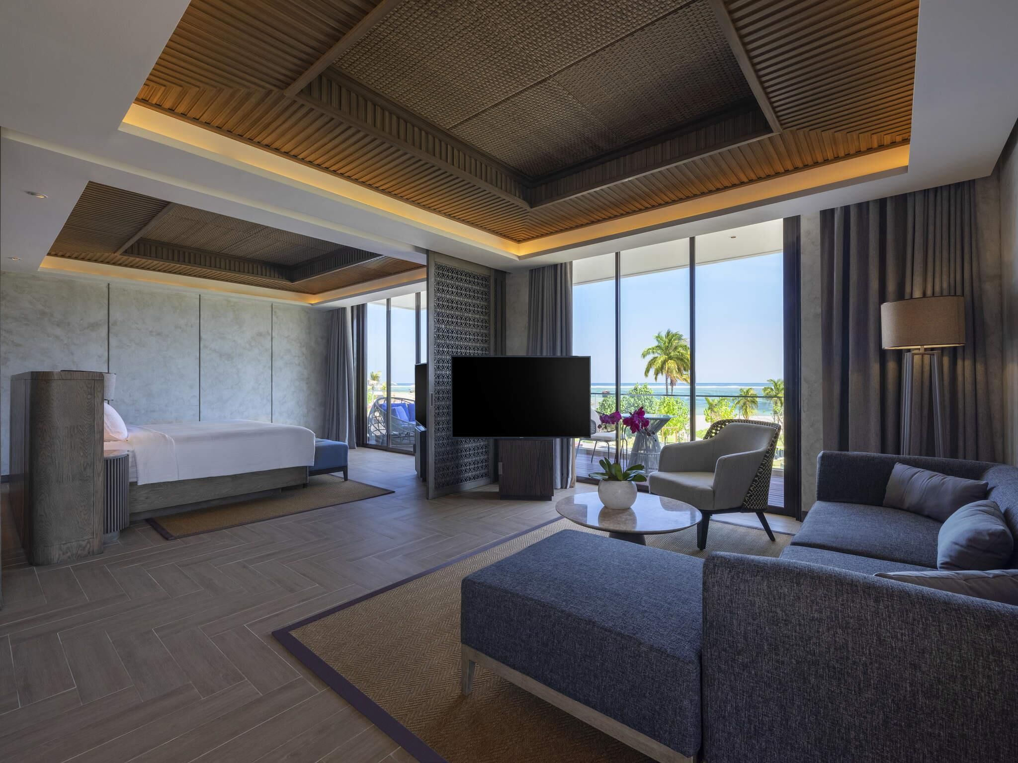 Een moderne hotelkamer met een bed, een bank, een televisie en een balkon met uitzicht.