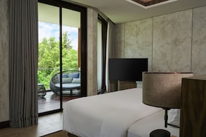 Hotelkamer met een groot bed, televisie, lamp en balkon met een rieten stoel en uitzicht op groen.