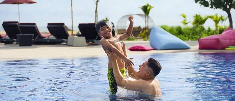 A swimming pool with lounge chairs and umbrellas in the background.