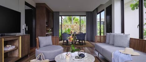 Una sala de estar moderna con sofá, sillones, una mesa de centro y televisor.