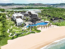 Un resort con piscina, playa y abundante vegetación.