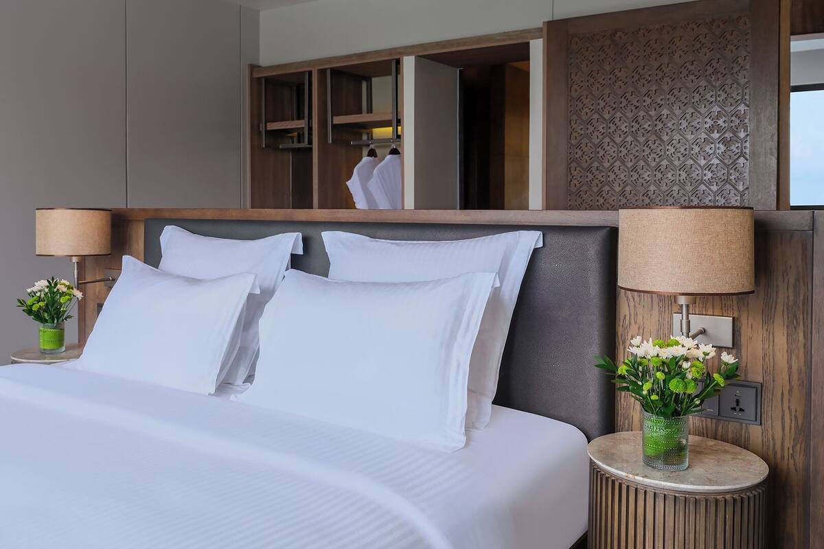 Une chambre d’hôtel moderne avec un grand lit, deux tables de chevet avec des lampes, un miroir et une armoire.