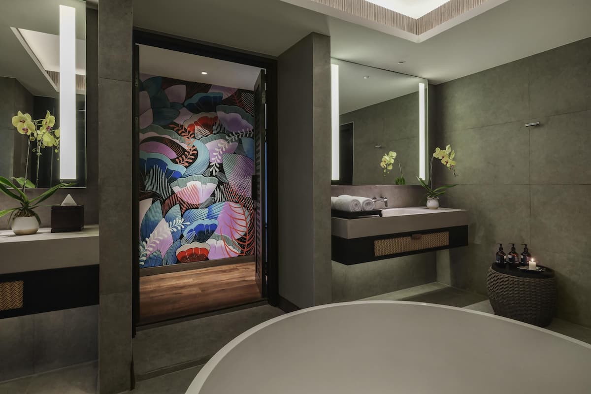 Un bany modern amb un mirall gran, una banyera, un lavabo amb tovalloles i una paret decorativa.