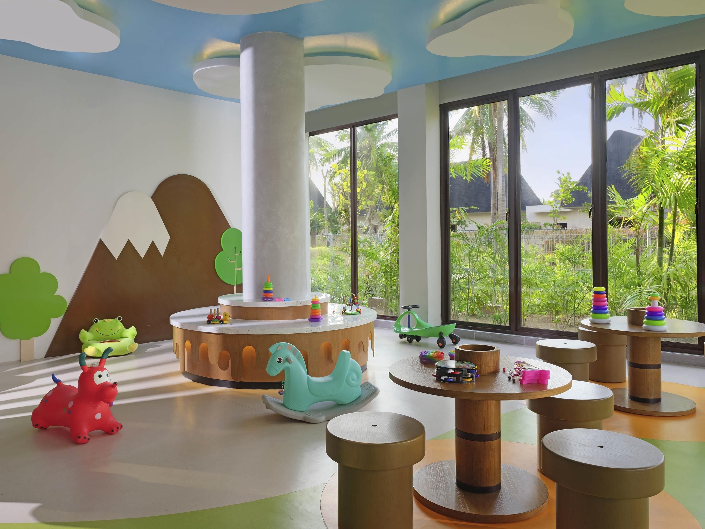 A children's play area with a large window, a central column, and various toys.