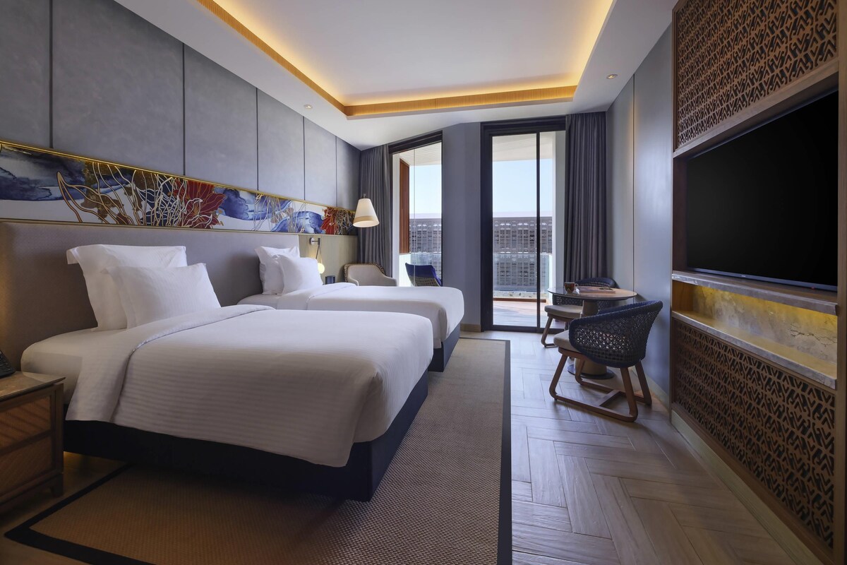 Une chambre d’hôtel avec un grand lit, un bureau, une chaise, une télévision et une vue sur la ville.