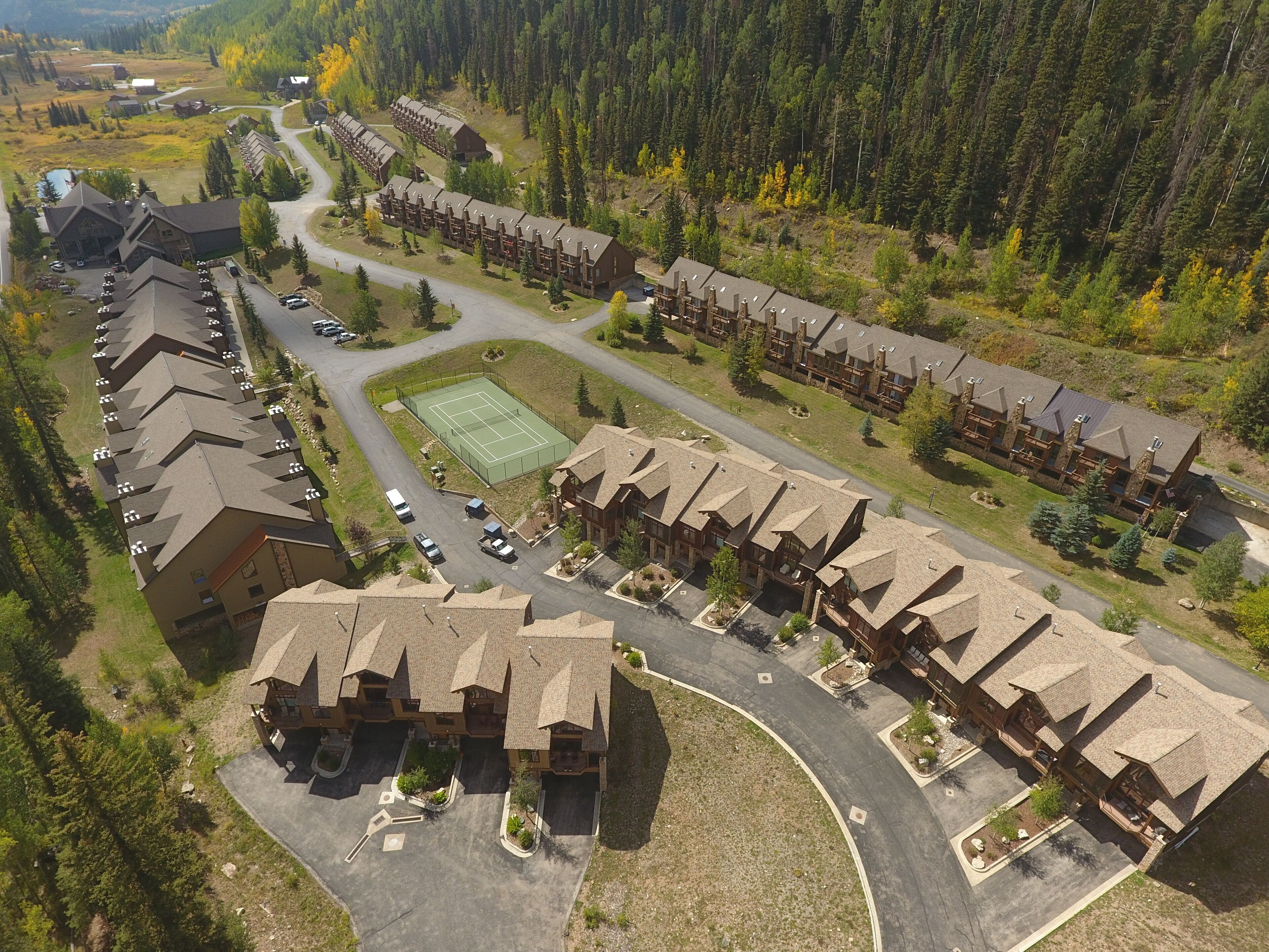 Un albergo con diversi edifici in stile chalet, un campo da tennis e un'area di parcheggio.