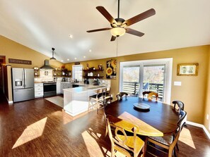 A spacious kitchen with a central island, modern appliances, and a dining area with a wooden table and chairs. - Wearadise Mountain Views Home features Hot Tub and Fire Pit by RedAwning (Sevierville)