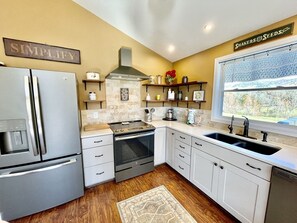 A kitchen with a stainless steel refrigerator, an oven, a sink, and a window with a view. - Wearadise Mountain Views Home features Hot Tub and Fire Pit by RedAwning (Sevierville)
