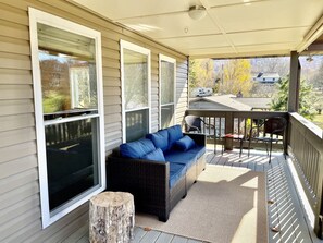 A covered porch with a sofa, a small table, and a chair.