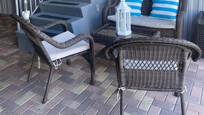 A covered outdoor area with wicker furniture, a small table, and a lantern. - Beautiful vacation mobile home at the Florida keys. (Key Largo)