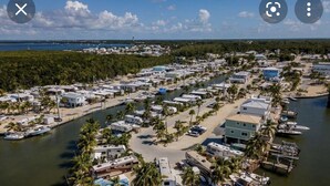 An aerial view of a marina with RVs and boats docked, surrounded by palm trees and a clear sky. - Beautiful vacation mobile home at the Florida keys. (Key Largo)