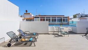 Una terrassa a la teulada amb gandules, una piscina i una zona de menjador.