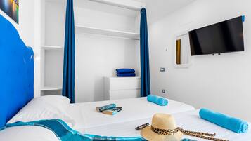 A hotel room with a bed, a TV, a wardrobe, and a window with curtains.