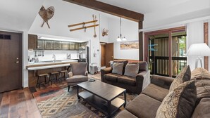 Ein modernes Wohnzimmer mit einer Couch, einem Couchtisch und einer Küchenzeile mit Barhocker.